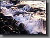 Warm light from the setting sun illuminates sea spray.